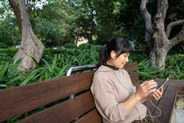istock An Asian woman sitting on a park bench using her phone 1709874152