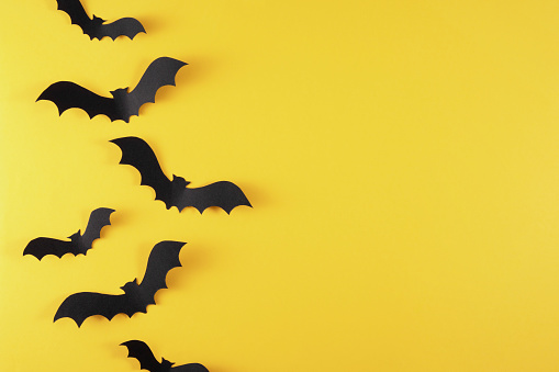 Halloween decorations, paper bats on yellow background with copy space