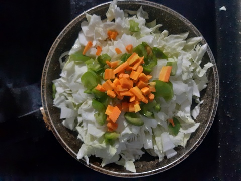 Beautifully arranged cabbage, carrots, onions, peppers in a frying pan, layered one on top of the other, a way to serve vegetables