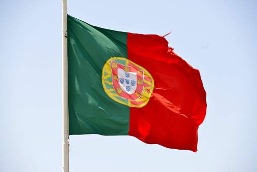 Flag of Portugal waving in the wind with ripped corners