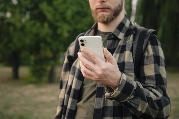 istock Man using white smartphone on blurred nature background, close up. 1709912712
