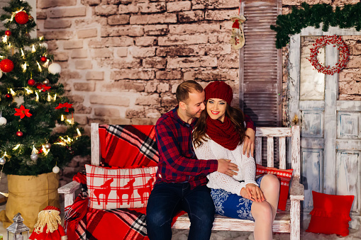 Nice couple sitting on the bench in a loft decorated for christmas party