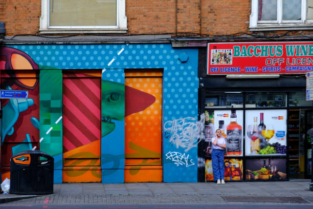 une femme parle sur son téléphone portable devant un magasin sans permis à spitalfields, dans l’est de londres. - off mot anglais photos et images de collection