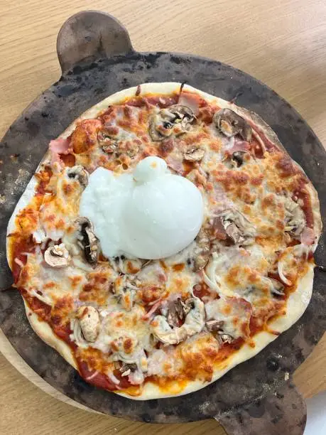 Homemade pizza on a pizza stone with buratta cheese toppings