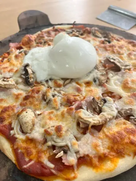 Homemade pizza on a pizza stone with buratta cheese toppings