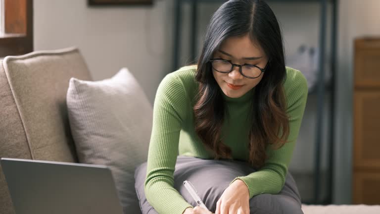 Young Asian businesswoman using a calculator to calculate business principles. Accounting statistics concept at the home office.