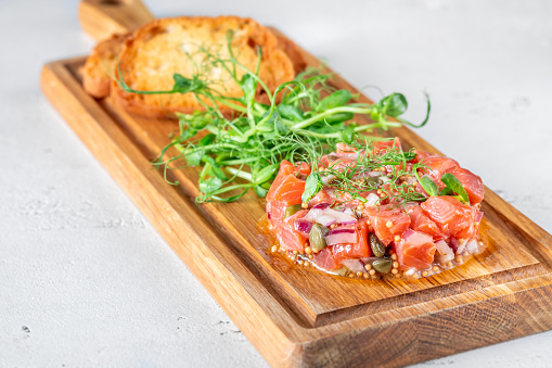 Portion of salmon tartare with bread and microgreen