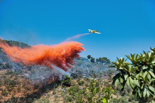 Firefighter dropping water in a Forest Fire during Day in Povoa de Lanhoso, Portugal.
