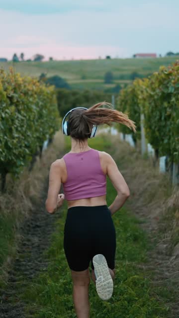 Female Jogger Running amidst Vine Plants in Vineyards - VERTICAL