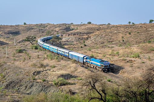 Express passenger coming out of a huge hill cutting in Ambale, Maharashtra, India.