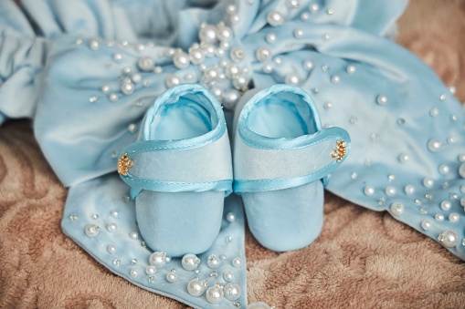 Baby booties of blue color for a boy lie on a blue bow.