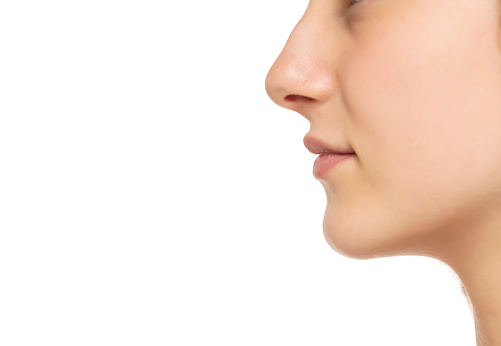 Closeup profile of female s nose and lips with no makeup on a white studio background