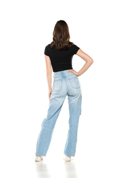 istock Young female model wearing jeans and black shirt posing on a white studio background. Back, rear view 1709982196