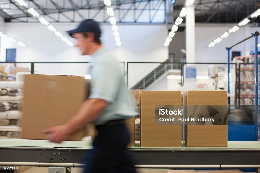 Worker carrying box in shipping area  Urgency Stock Photo