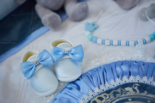 Small baby booties with jewelry are lying on the table. The concept of waiting for a newborn.