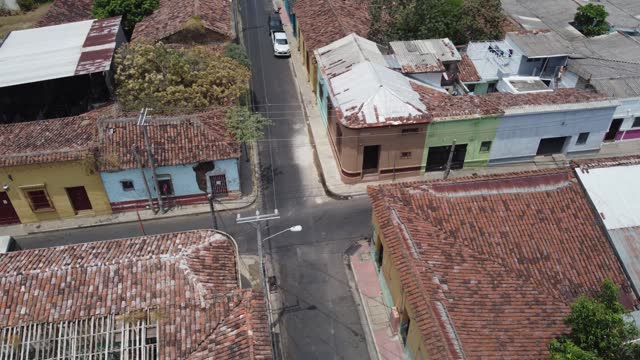 Rotating aerial: Bus and motos in narrow San Salvador city streets