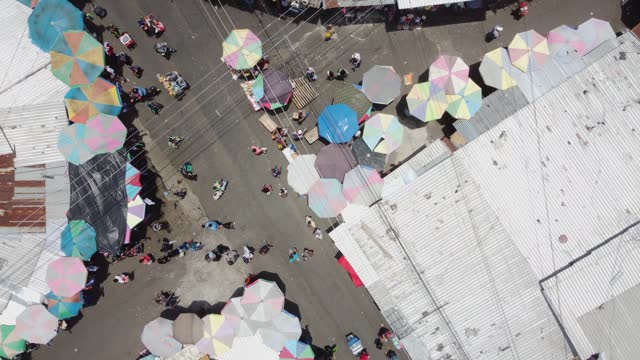 Rotating aerial descends to street market intersection, San Salvador