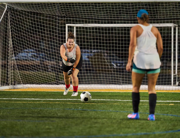 Young woman goalie defending goal during a practice session on soccer field