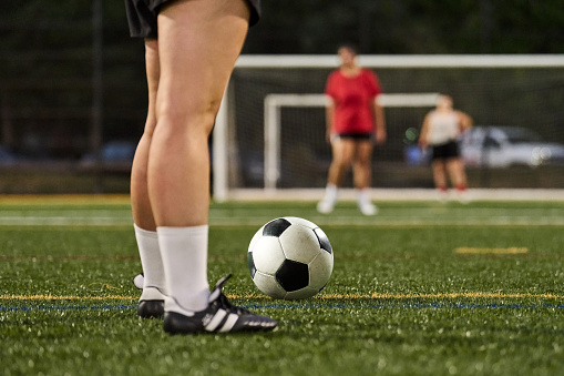 Low angle close-up of a female players practising soccer on outdoors grass pitch