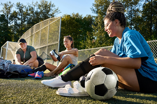 Group of young female soccer players getting ready for a team practice outside on a sports field