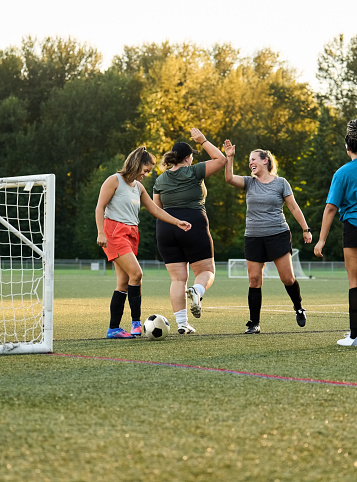 Female soccer players giving each other high fives while playing a pick-up game on soccer field