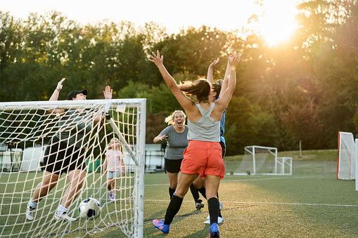 Group of women players cheering and celebrating a goal during team practice session on outdoors field