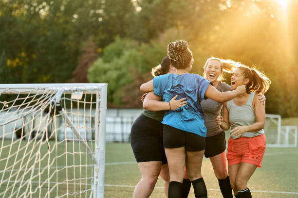 Female soccer players cheering and huddling while team practice on field