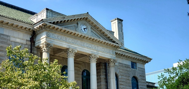 In Decatur, United States the Dekalb County Courthouse entrance is marked with columns and a large clock.