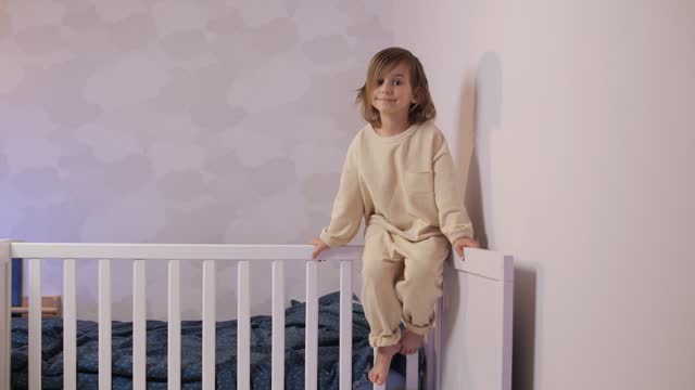 portrait of a little girl sitting on the bed in pajamas