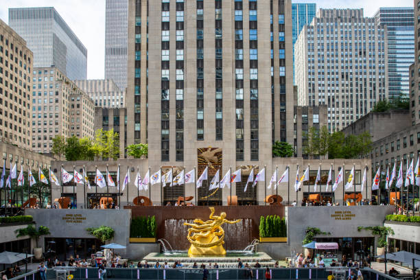 Vertorama of the Golden Prometheus statue and fountain in the Lower Plaza at Rockerfeller Center Rockefeller Center , New York, USA - September 15, 2023.  A landscape of the golden Prometheus sculpture and fountain in the Lower Plaza of The Rockerfeller Center in New York City with people skating rockefeller ice rink stock pictures, royalty-free photos & images