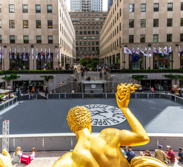 Vertorama of the Golden Prometheus statue and fountain in the Lower Plaza at Rockerfeller Center Rockefeller Center , New York, USA - September 15, 2023.  A landscape of the golden Prometheus sculpture and fountain in the Lower Plaza of The Rockerfeller Center in New York City with people skating rockefeller ice rink stock pictures, royalty-free photos & images
