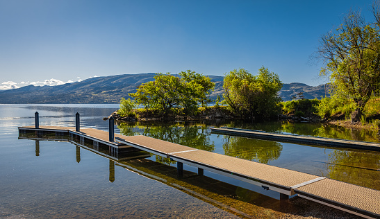 Wooden dock on a calm lake on beautiful summer morning, Okanagan Lake, Canada. Travel photo, nobody, copy space for text