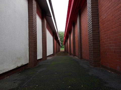 Two different coloured walls in a side by side form split by a black asphalt walkpath. When seen historically remiscining the battle of hastings between armies of the red and white roses.