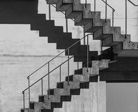 Abstract architecture background, square concrete stairway perspective, stairwell, black and white photo. Minimalism architecture. Modern architecture with distinguishing shades of black and white.