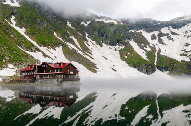 Balea Lake cottage, Fagaras mountains Balea Lake cabin reflecting in the lake, Fagaras mountains balea lake romania stock pictures, royalty-free photos & images
