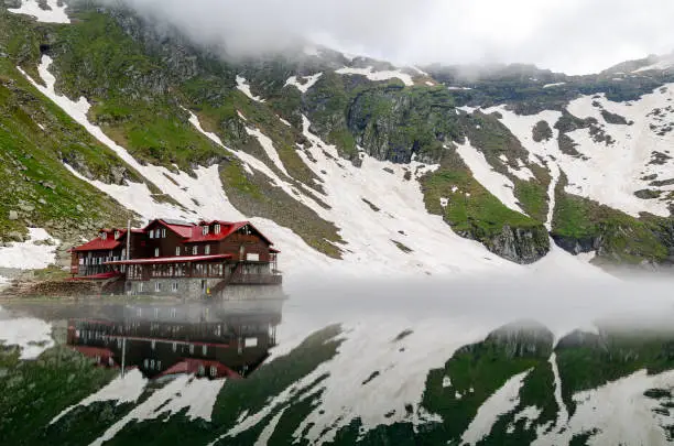 Balea Lake cabin reflecting in the lake, Fagaras mountains