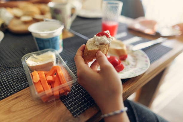 Closeup of teenage girl having breakfast Teenage girl having a breakfast. She is eating bread with cheese and tomato and drinking juice.
Shot with Canon R5 london girl stock pictures, royalty-free photos & images