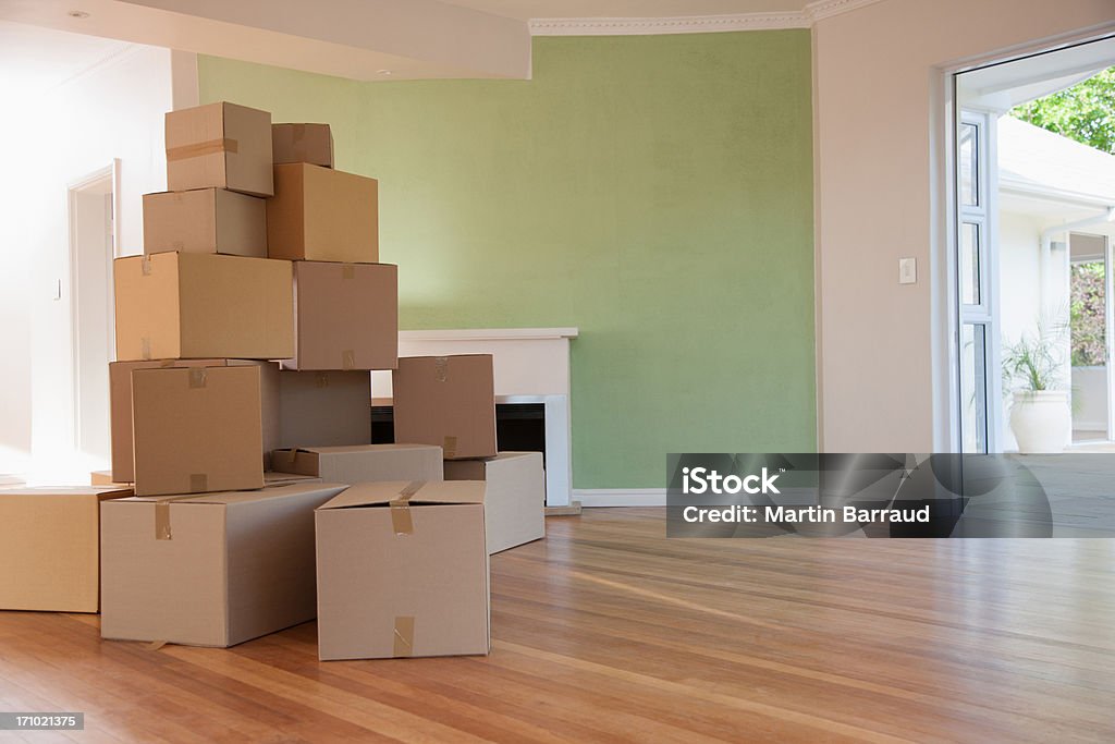 Boxes stacked in living room of new house  Relocation Stock Photo