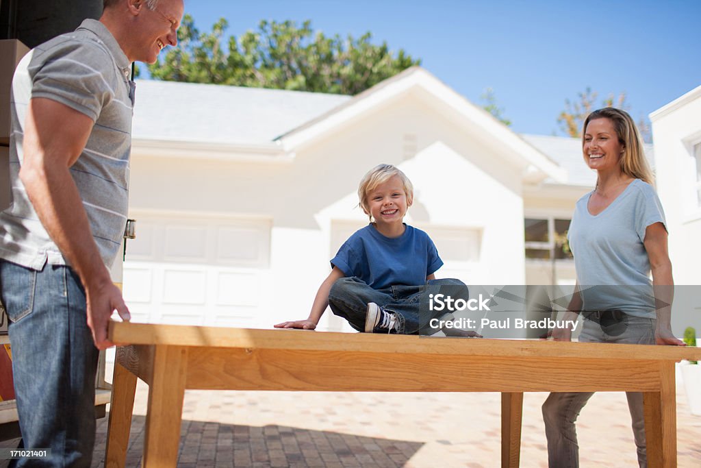 Parents and son moving table from moving van into house  Carrying Stock Photo