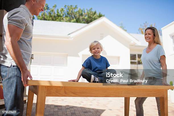 Parents And Son Moving Table From Moving Van Into House Stock Photo - Download Image Now