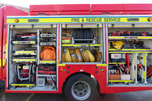 A fireman stands in front of a fire truck in a garage