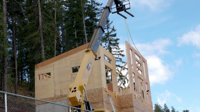 View of crane helping to  erect large front wall of home