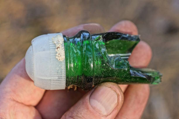 istock hand holding one old glass sharp green neck of a broken bottle with white plastic stopper 1710384162