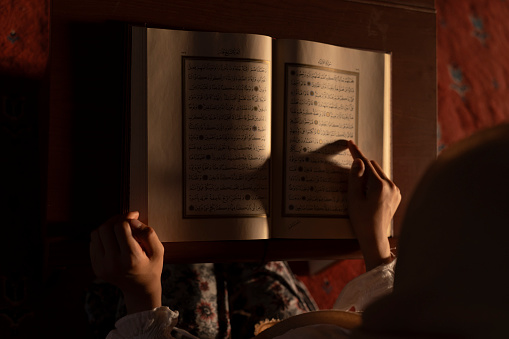 A girl reading the Koran in a mosque. Reading the Koran, the holy book of Islam. Girl praying in a mosque. Worship during Ramadan.   Miraj Kandil. Laylat al-Qadr. Regaip Kandil.