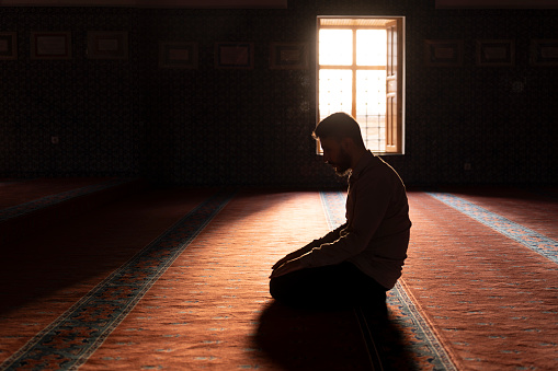 Muslim man worshipping in a mosque. Young man praying in a mosque. Worship during Ramadan. Islamic life.