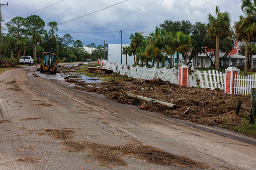 Grader leveling and clearing road after storm landfall in Steinhatchee, Norh Florida. Broken fence and wreckage line the road