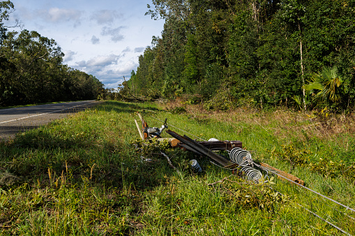 Power grid malfunction in North Florida: electric pole and transformer lying on the grass by highway after hurricane