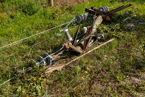 Power infrastructure disturbance after storm in North Florida: electric telephone pole and power transformer lying on the grass by the highway