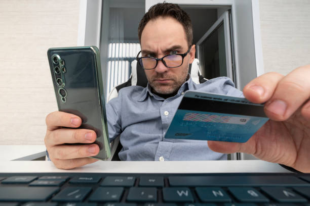 Online shopping concept. Happy Arab businessman holding credit card and smartphone, making e-payment, ordering goods on web, purchasing stuff on internet at his office Online shopping concept. Happy Arab businessman holding credit card and smartphone, making e-payment, ordering good on web, purchasing stuff on internet at his office cvc stock pictures, royalty-free photos & images