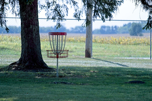 Red with silver chain frisbee golf holes on stands in a small community park